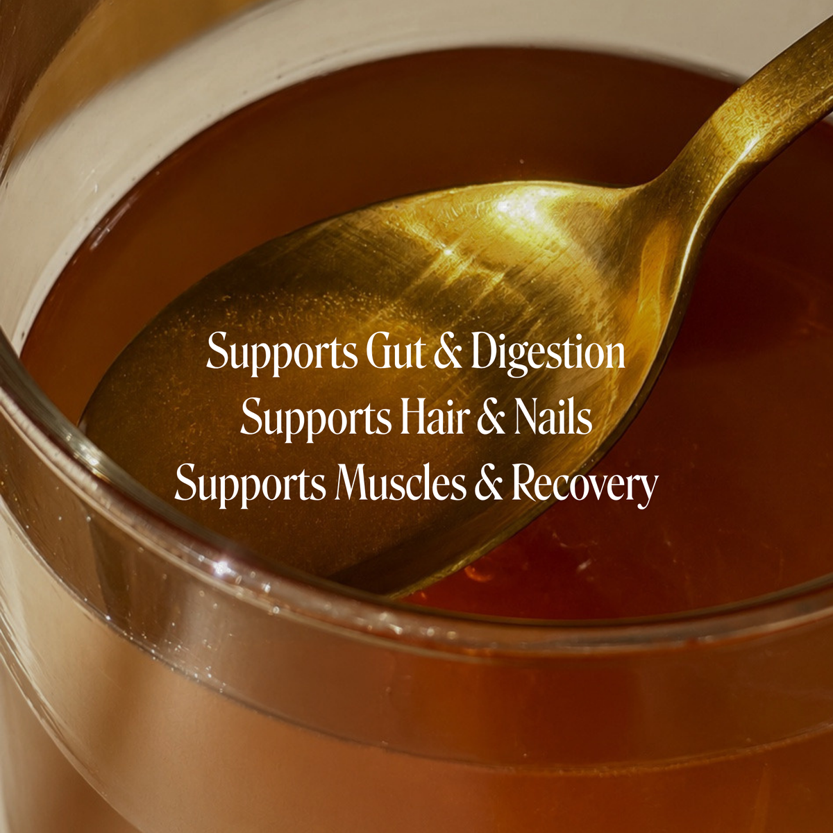 A close-up of a golden spoon resting in a clear glass cup filled with amber-brown liquid, with white text overlay reading 'Supports Gut & Digestion', 'Supports Hair & Nails', and 'Supports Muscles & Recovery'.
